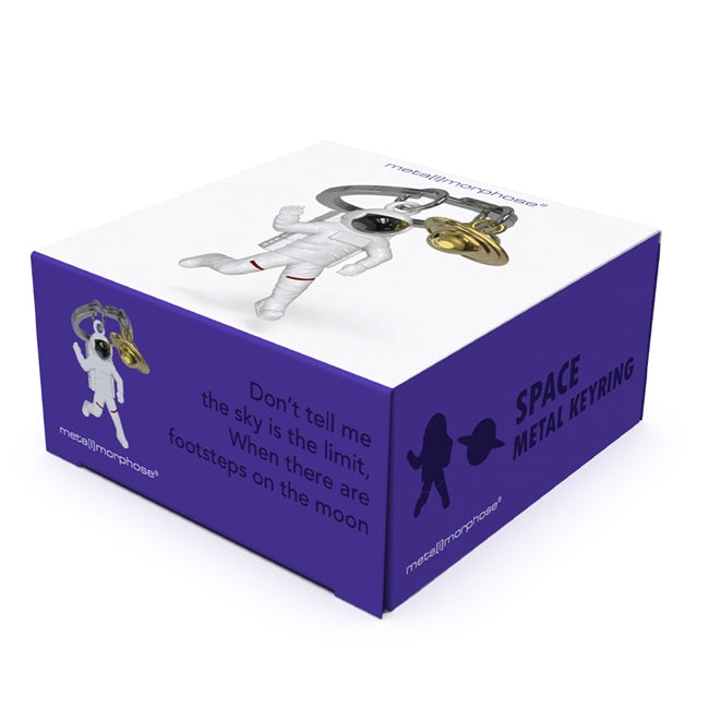 Metalmorphose.lt metalinis raktų pakabukas ASTRONAUTAS. Baltas metalinis astronauto kostiumas, nudažytas auksinis Saturno simbolis, 3D kosminė miniatiūra. Nerūdijančio plieno žiedas. Pakabukas iš KELIONIŲ PASAULIS kolekcijos.
