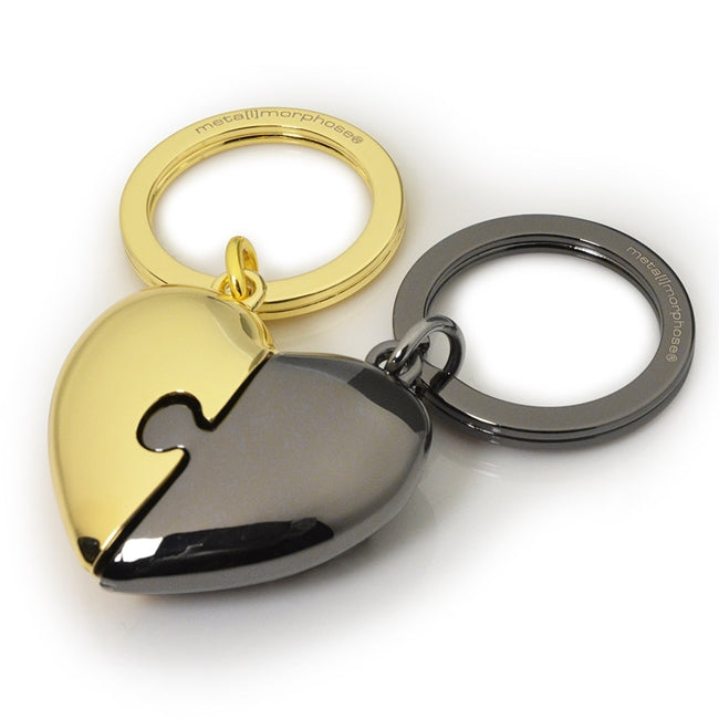 Metalmorphose.lt metalinis raktų pakabukas DVI ŠIRDYS. Auksinė ir juoda širdelės, sujungtos kaip romantiška dėlionė. Premium metalas. MEILĖS PASAULIS kolekcija.