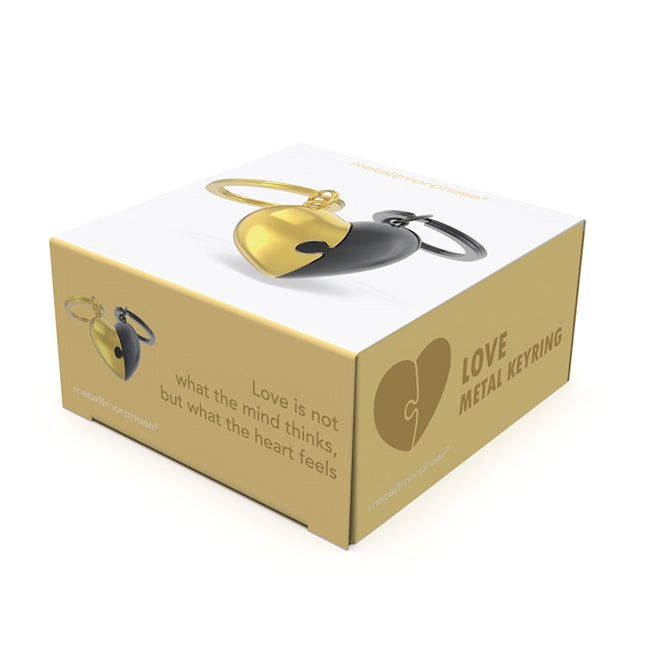 Metalmorphose.lt metalinis raktų pakabukas DVI ŠIRDYS. Auksinė ir juoda širdelės, sujungtos kaip romantiška dėlionė. Premium metalas. MEILĖS PASAULIS kolekcija.