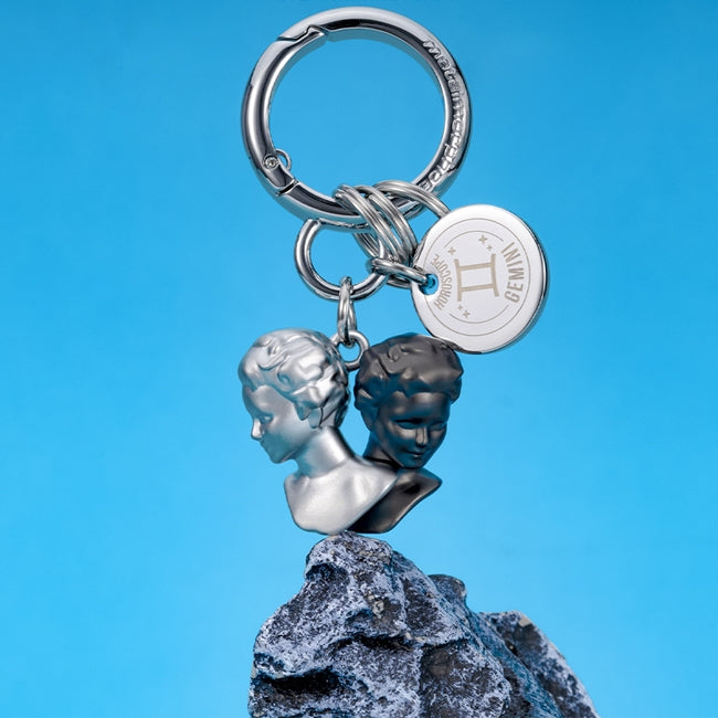 Metalmorphose.lt metalinis raktų pakabukas DVYNIAI. Du juodas ir baltas, stilizuoti veidai, oro ženklo simbolika, premium metalo miniatiūra, nerūdijančio plieno žiedas. Pakabukas iš ZODIAKŲ PASAULIS kolekcijos.