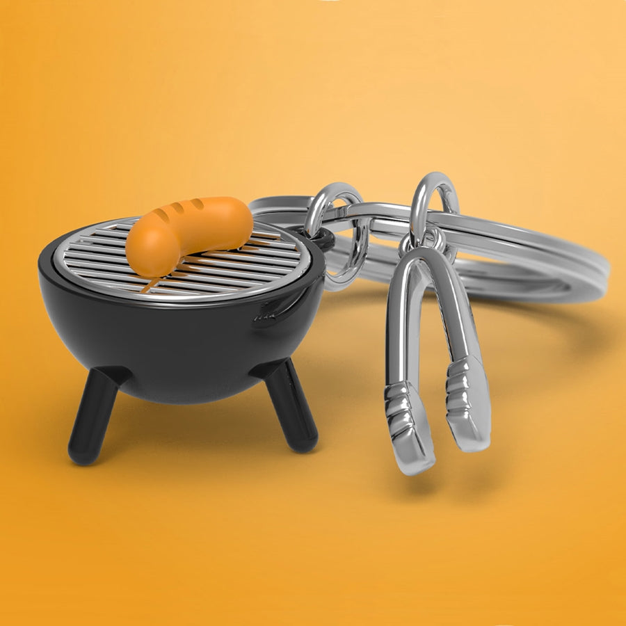 Metalinis raktų pakabukas „Grilius“ su BBQ mentelės ir žnyplių dizainu, Metalmorphose „Skonių Pasaulis“ kolekcija.
