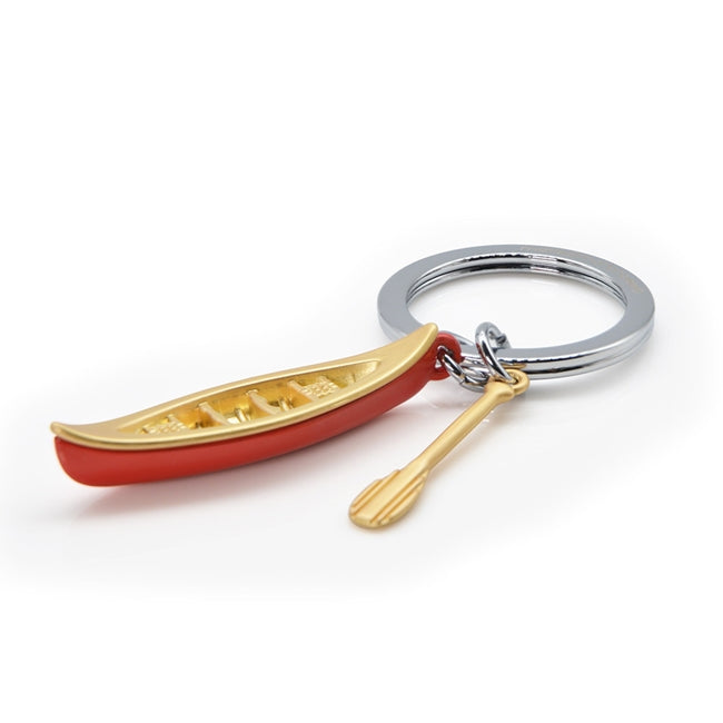 Metalmorphose.lt metalinis raktų pakabukas KANOJOS KELIAS. Raudona kanoja ir auksinis irklas, detalus 3D vandens nuotykių simbolis. Premium cinko lydinys, nerūdijančio plieno žiedas. Pakabukas iš KELIONIŲ PASAULIS kolekcijos.