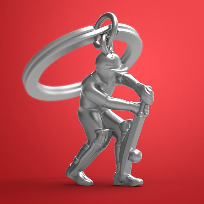 Metalmorphose.lt metalinis raktų pakabukas KRIKETO ŽAIDĖJAS. 3D kriketo žaidėjo siluetas su lazda, premium cinko lydinys, sporto miniatiūra, plieno žiedas. Iš SPORTO PASAULIS kolekcijos.