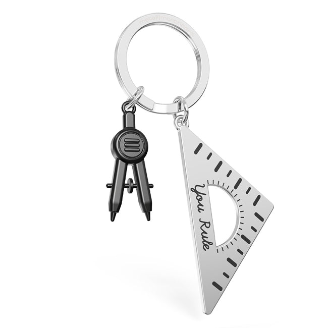 Metalmorphose.lt metalinis raktų pakabukas LINIUOTĖS VALDOVAS. Sidabrinis cinko lydinio korpusas, nudažytos skaičių ir linijų detalės, 3D liniuotės miniatiūra. Nerūdijančio plieno žiedas. Raktų pakabukas iš KASDIENYBĖS PASAULIS kolekcijos.