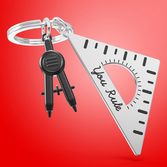 Metalmorphose.lt metalinis raktų pakabukas LINIUOTĖS VALDOVAS. Sidabrinis cinko lydinio korpusas, nudažytos skaičių ir linijų detalės, 3D liniuotės miniatiūra. Nerūdijančio plieno žiedas. Raktų pakabukas iš KASDIENYBĖS PASAULIS kolekcijos.