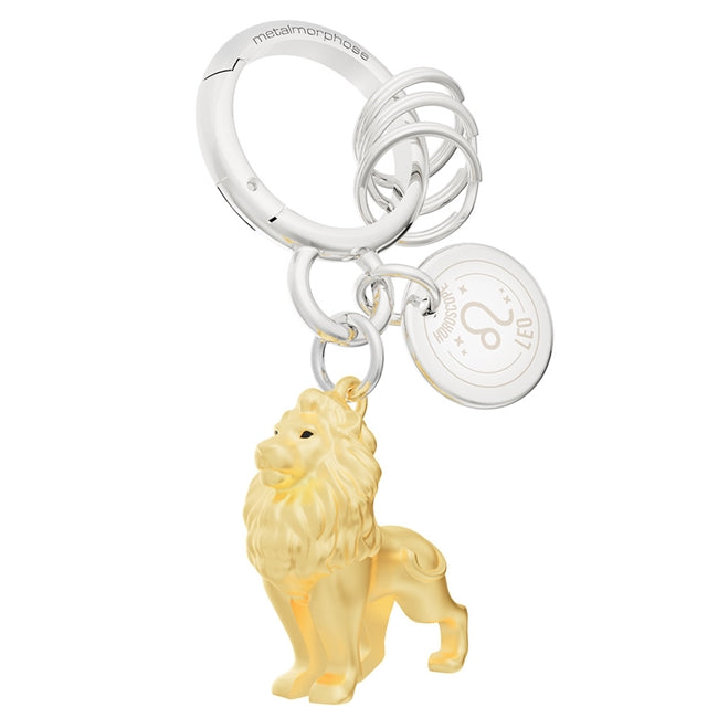 Metalmorphose.lt metalinis raktų pakabukas LIŪTAS. Karališka auksinio liūto galva su detaliais karčiais, saulės ženklo simbolika, premium cinko lydinys ir plieno žiedas. Pakabukas iš ZODIAKŲ PASAULIS kolekcijos.