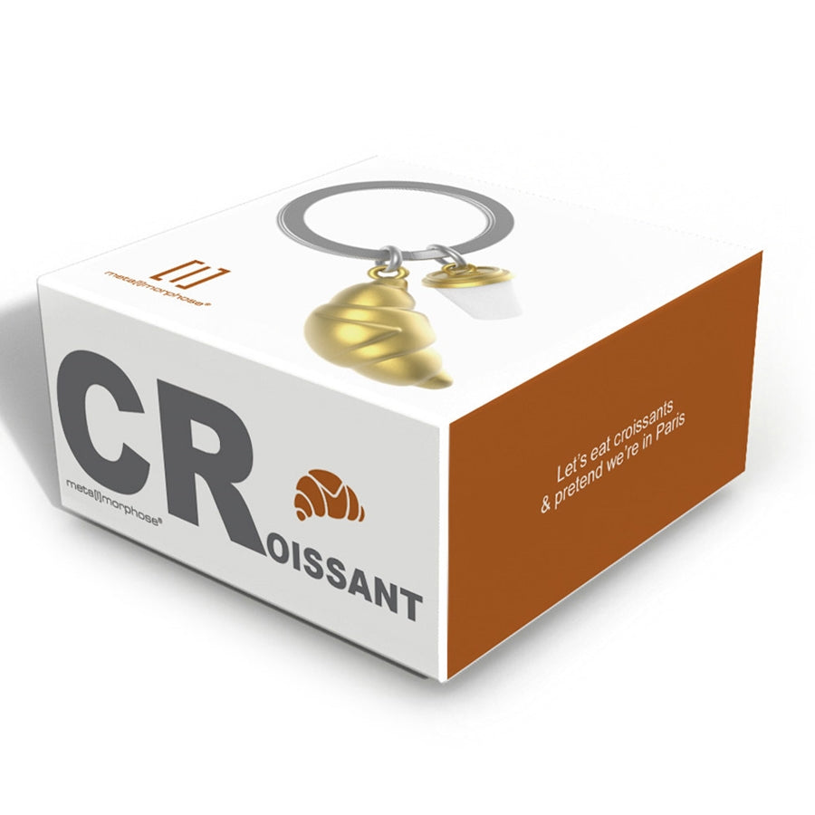 Metalmorphose metalinis raktų pakabukas „Pasimatymas Paryžiuje“ – 3D kruasano ir kavos puodelio dizainas iš Skonių Pasaulis kolekcijos. Detalės auksinis dangtelis, auksinė kruasano tekstūra, plieninis žiedas