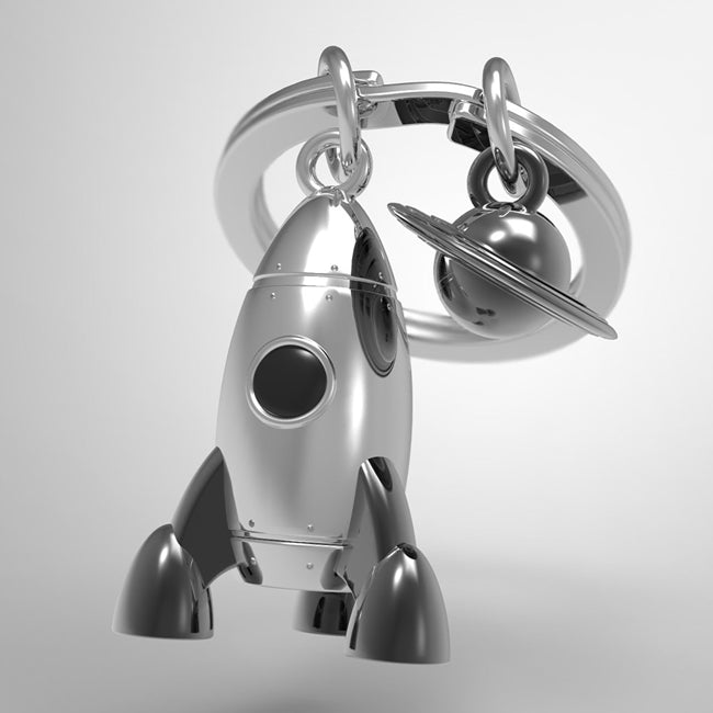 Metalmorphose.lt metalinis raktų pakabukas RAKETA Į SATURNĄ. Metalinis raketos korpusas, nudažyti liepsnos akcentai, 3D kosminės raketos miniatiūra. Nerūdijančio plieno žiedas. Pakabukas iš KELIONIŲ PASAULIS kolekcijos.