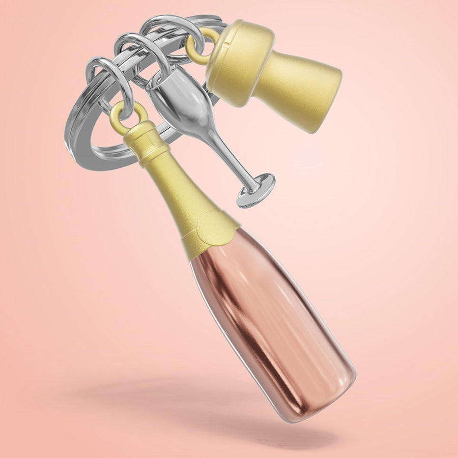 Metalmorphose metalinis raktų pakabukas „Rožinė Šampano Akimirka“ – rožinio šampano 3D butelis su taure ir kamščiu iš Skonių Pasaulis kolekcijos.