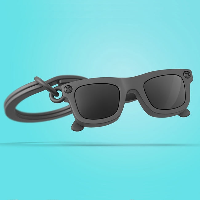 Metalmorphose.lt metalinis raktų pakabukas SAULĖS AKINIAI. Juodi blizgūs akiniai, detalizuotas 3D miniatiūros rėmelis, premium metalo paviršius. Nerūdijančio plieno žiedas. Pakabukas iš KELIONIŲ PASAULIS kolekcijos.