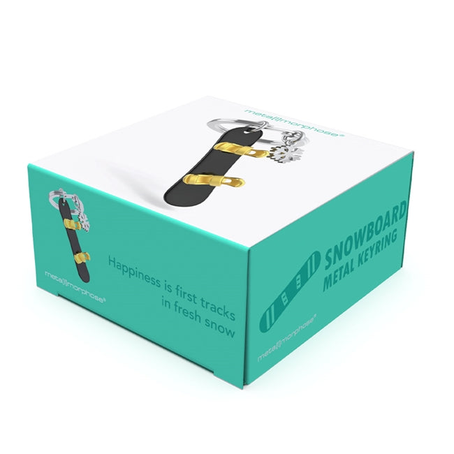 Metalmorphose.lt metalinis raktų pakabukas SNIEGLENTĖ IR SNAIGĖ. Juoda 3D snieglentė su auksiniais segtuvais, šalia spindinti metalinė snaigė, premium cinko lydinys, plieno žiedas. SPORTO PASAULIS kolekcija.