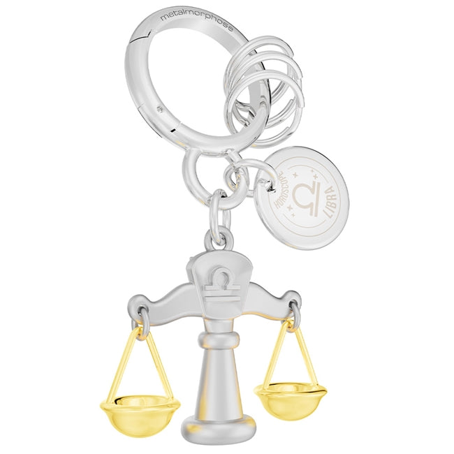 Metalmorphose.lt metalinis raktų pakabukas SVARSTYKLĖS. Delikati svarstyklių miniatiūra, auksinės detalės, oro ženklo simbolika, premium cinko lydinys ir plieno žiedas. Pakabukas iš ZODIAKŲ PASAULIS kolekcijos.