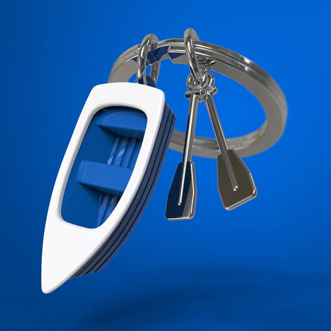 Metalmorphose.lt metalinis raktų pakabukas ŽVEJO VALTELĖ. Metalinis korpusas, mėlyni valties kraštai, 3D valties su irklais miniatiūra. Nerūdijančio plieno žiedas. Pakabukas iš KELIONIŲ PASAULIS kolekcijos.